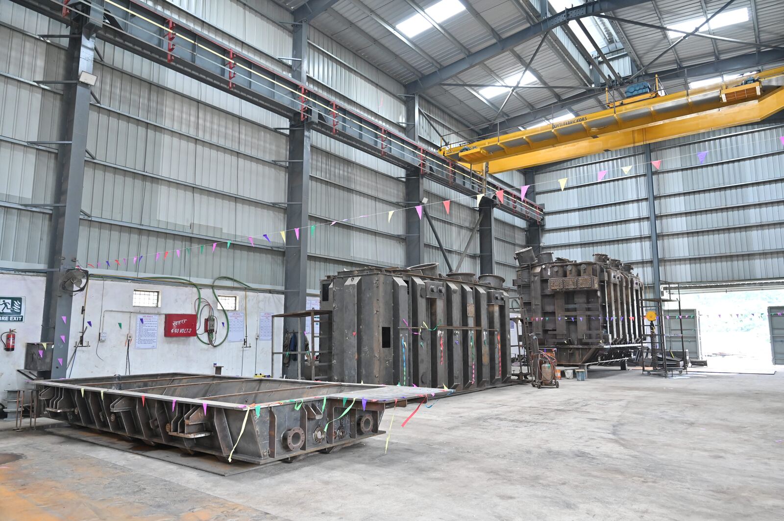 Large fabricated steel tanks under construction in a high-bay workshop with an overhead crane